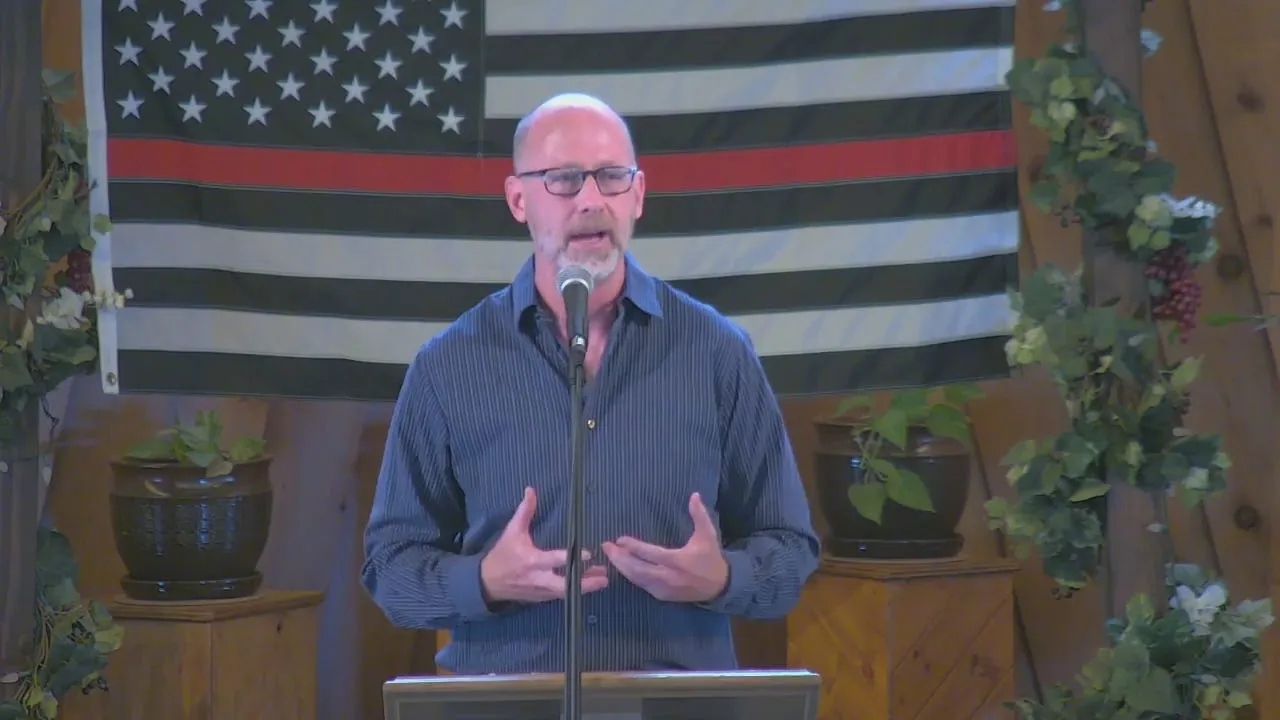 Dr. McDonald standing in front of the podium before an American flag at Calvary Chapel of the Canyons