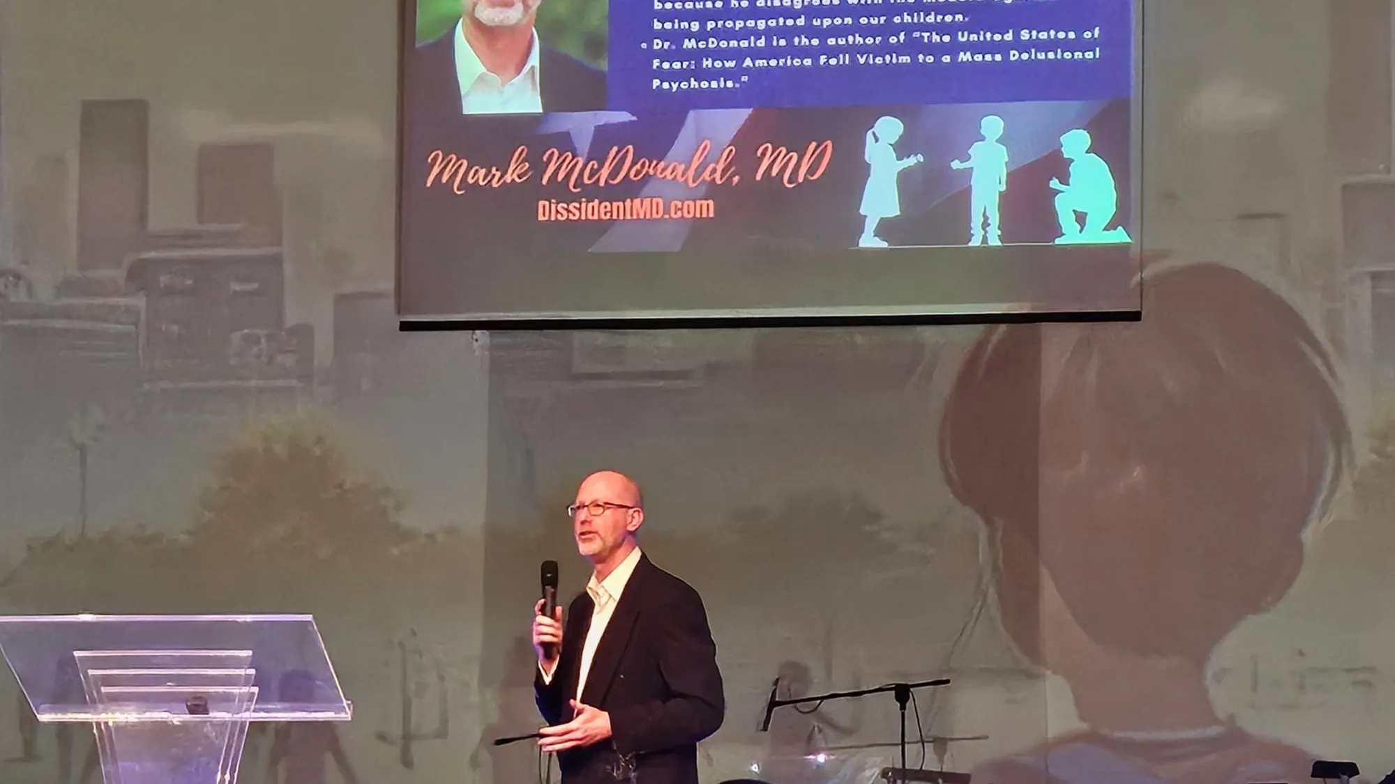 Dr. Mark McDonald on stage with "Save Our Children" in the background
