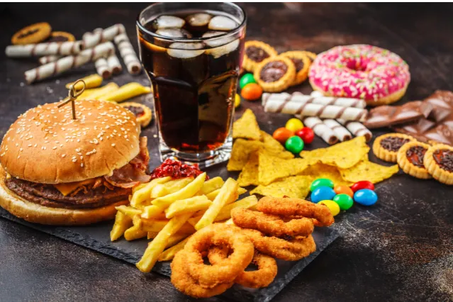 Array of junk food--burgers, onion rings, fries, chips, donuts, cookies on a table
