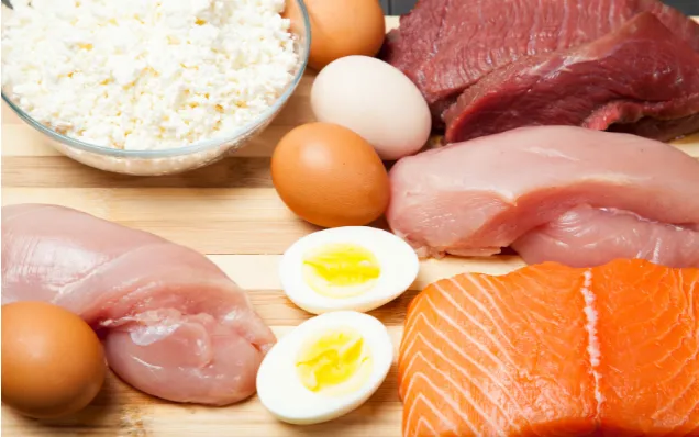 Raw meat, fish, eggs, and cheese laid out on butcher block