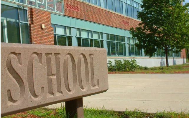 School sign with building behind it