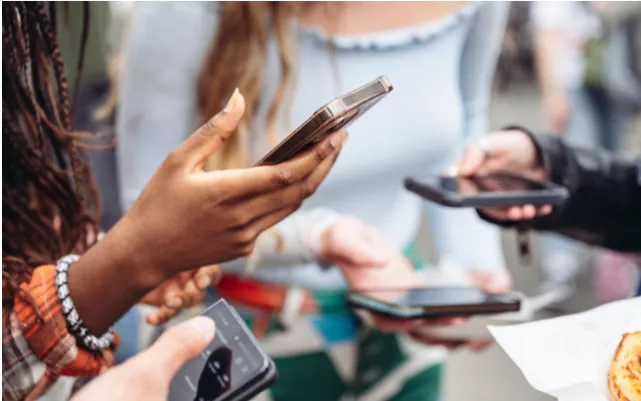 Gaggle of teens holding their cell phones and swiping