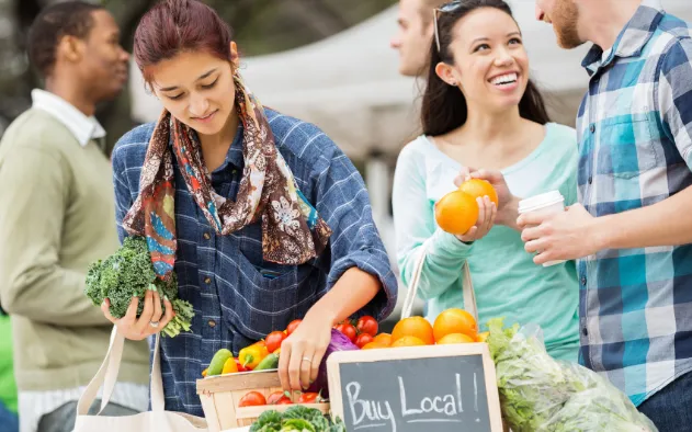 Customers looking over fruits and vegetables at a local farmers market