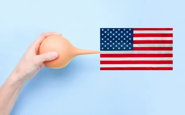 Hand holding an enema to the American flag