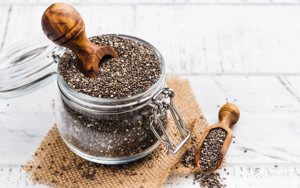 Mason jar full of chia seeds with wooden scooper sticking out